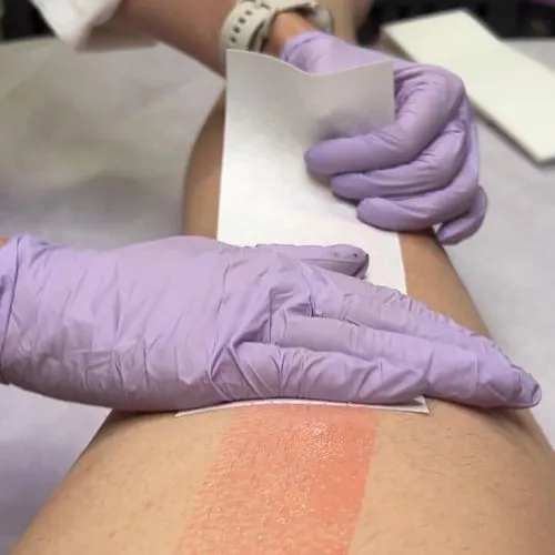 Aesthetician performing a waxing treatment, with a focus on the precision and gentle care of the client's skin.